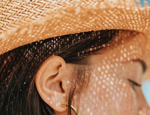 Woman with fair skin wears a hat to protect her from the sun