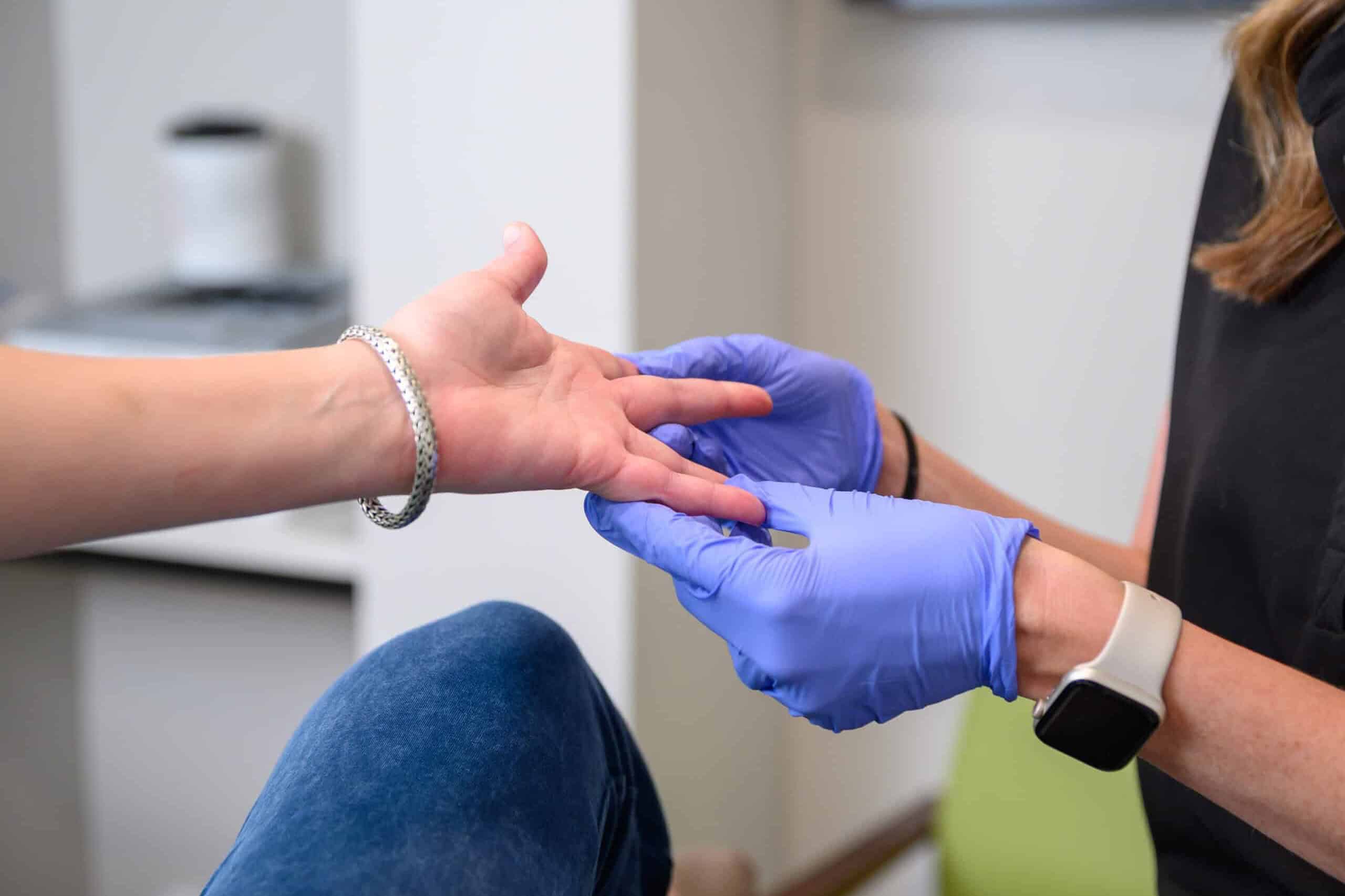 A provider at True Dermatology checks a patient's hand for medical dermatology issues