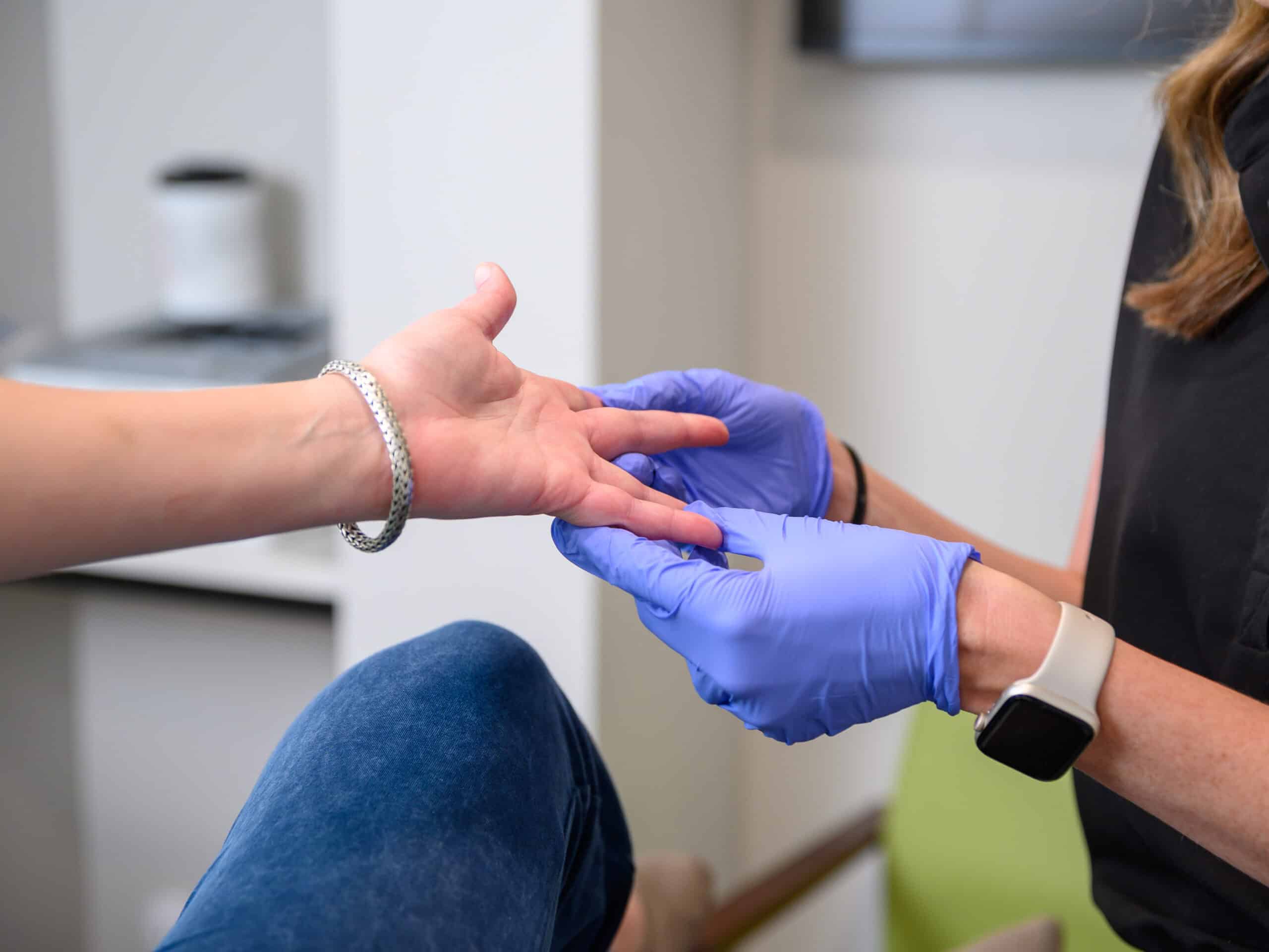 A provider at True Dermatology checks a patient's hand for medical dermatology issues